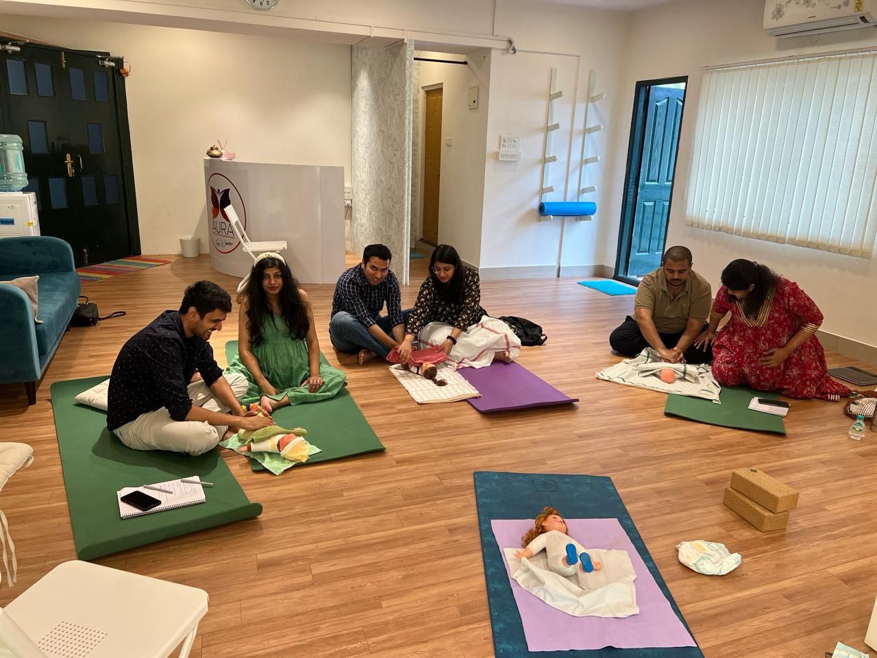 Image of parents learning infant care in a newborn care workshop by Aura Birthing Partner.
